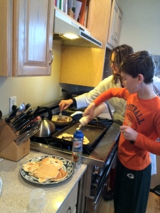 Family members cooking breakfast including pancake artwork