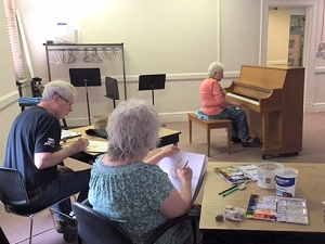 Dorothy plays piano while modeling for watercolor class at The Center