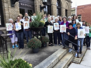Participants at a watercolor workshop led by Janet Rogers, posed with their paintings