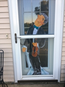 Foamcore cutout of teacher holding violin by Jo Myers-Walker, posed inside screen door
