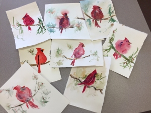 Watercolor paintings of cardinal birds by several students in a variety of styles