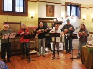 Group of ukulele players performs amid displays at an art show