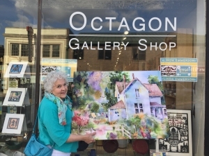 Artist Jo Myers-Walker poses in front of the Octagon Gallery Shop in Ames, Iowa with fabric print of one of her watercolor paintings