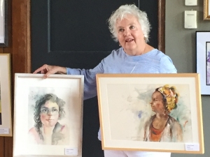 Jo Myers-Walker with two of her paintings, watercolor portraits of women, accepted into the IWS 2019 Annual Exhibition