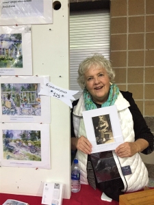 Jo Myers-Walker at table holding photo of friend who passed away from ALS