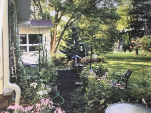 Photo of a backyard garden in summer with flowers and patio chairs
