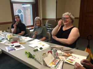 Members of a watercolor workshop at a table with watercolor supplies