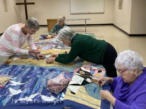 Skilled assistants work with artist Jo Myers-Walker on revisions to the fabric Easter story wall hanging