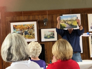 Watercolorist Andy Evansen holds up a demonstration painting at the 2025 Iowa Watercolor Society Annual Meeting