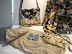 An assortment of fabric repurposing projects by Jo Myers-Walker including a shoulder bag, tailored blouse, glasses pouch, and mended garment