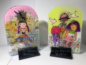 Clocks made from clear plastic with colorful designs in the style of a child's drawings